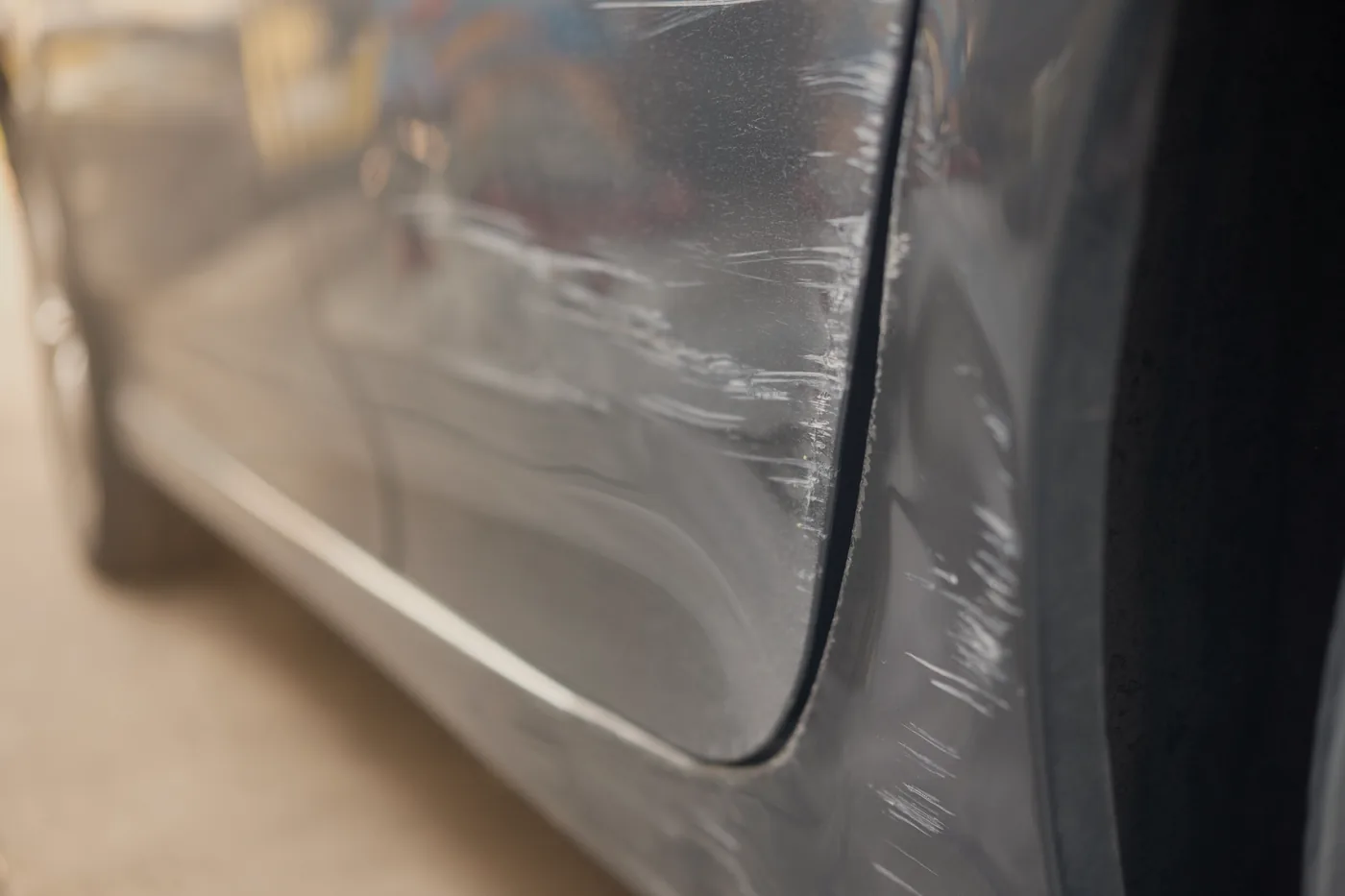 Deep scratches scored into the door and rear quarter panel of a dark grey car